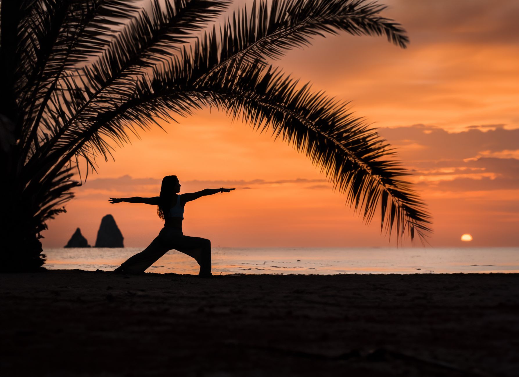 silhouette of woman practicing yoga at sunset beach